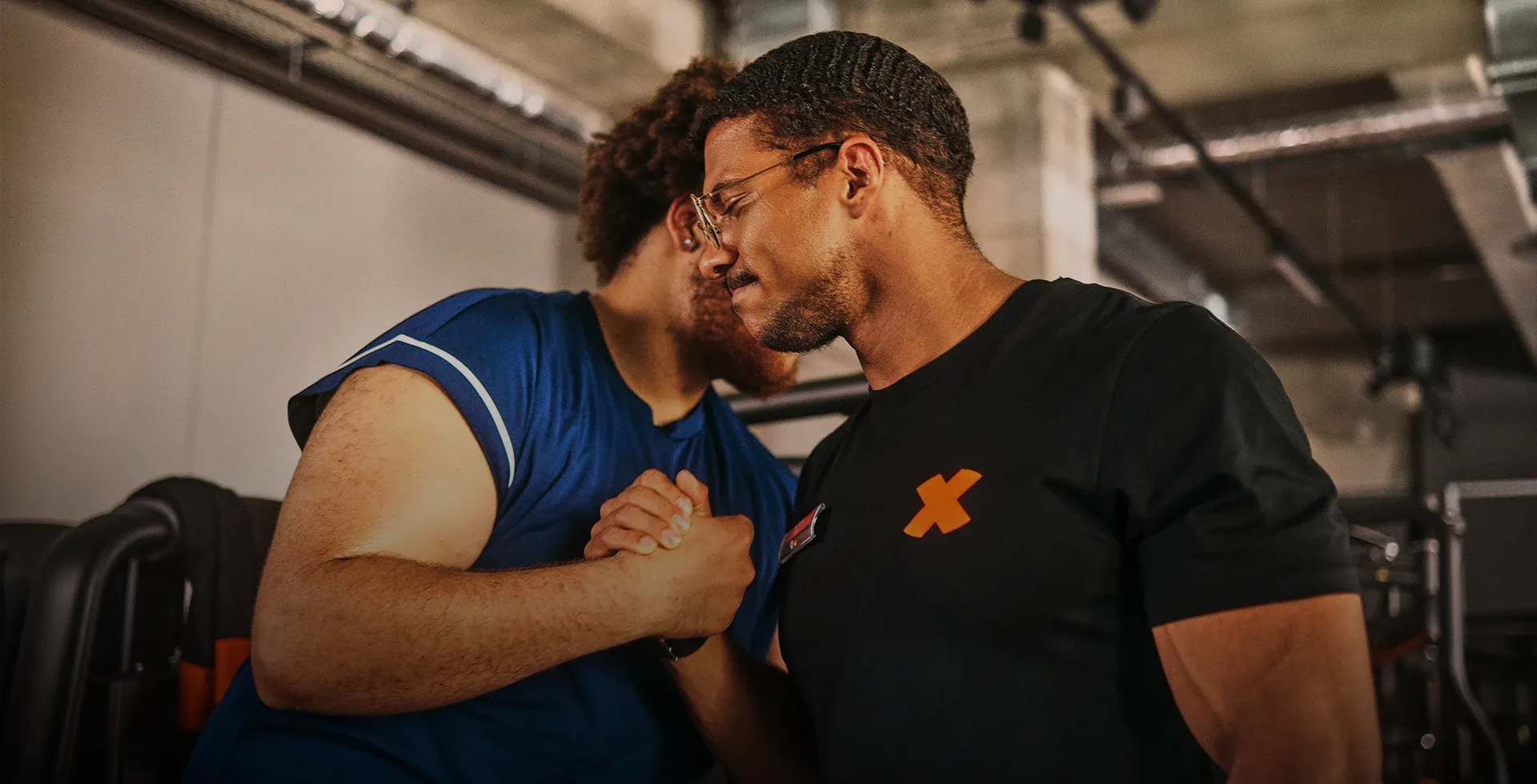 Bild: FitX-Trainer und Mitglied begrüßen sich im Fitness-Studio mit Handschlag; darüber steht die Karrieremessage „Bauch, Beine, Bewerbung