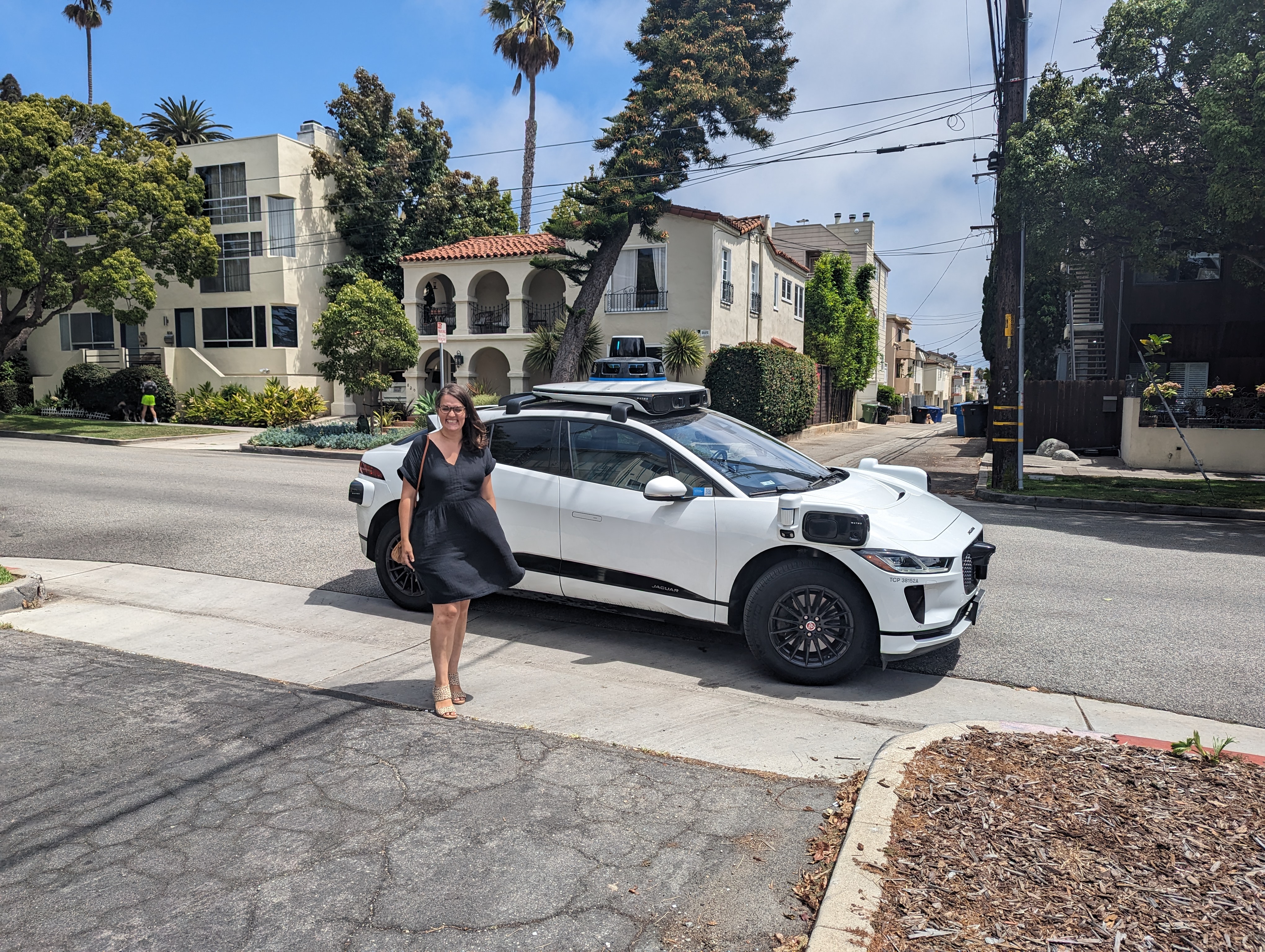 Sarah Wilson, executive director of Harvest Home, standing outside in Santa Monica next to a parked Waymo One vehicle