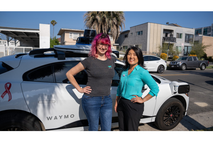 Waymo engineer and YMCA leader stand in front of a Waymo autonomous vehicle in Los Angeles