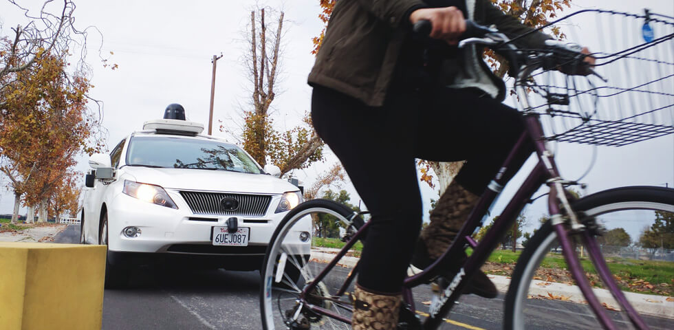 Waymo car driving behind a biker