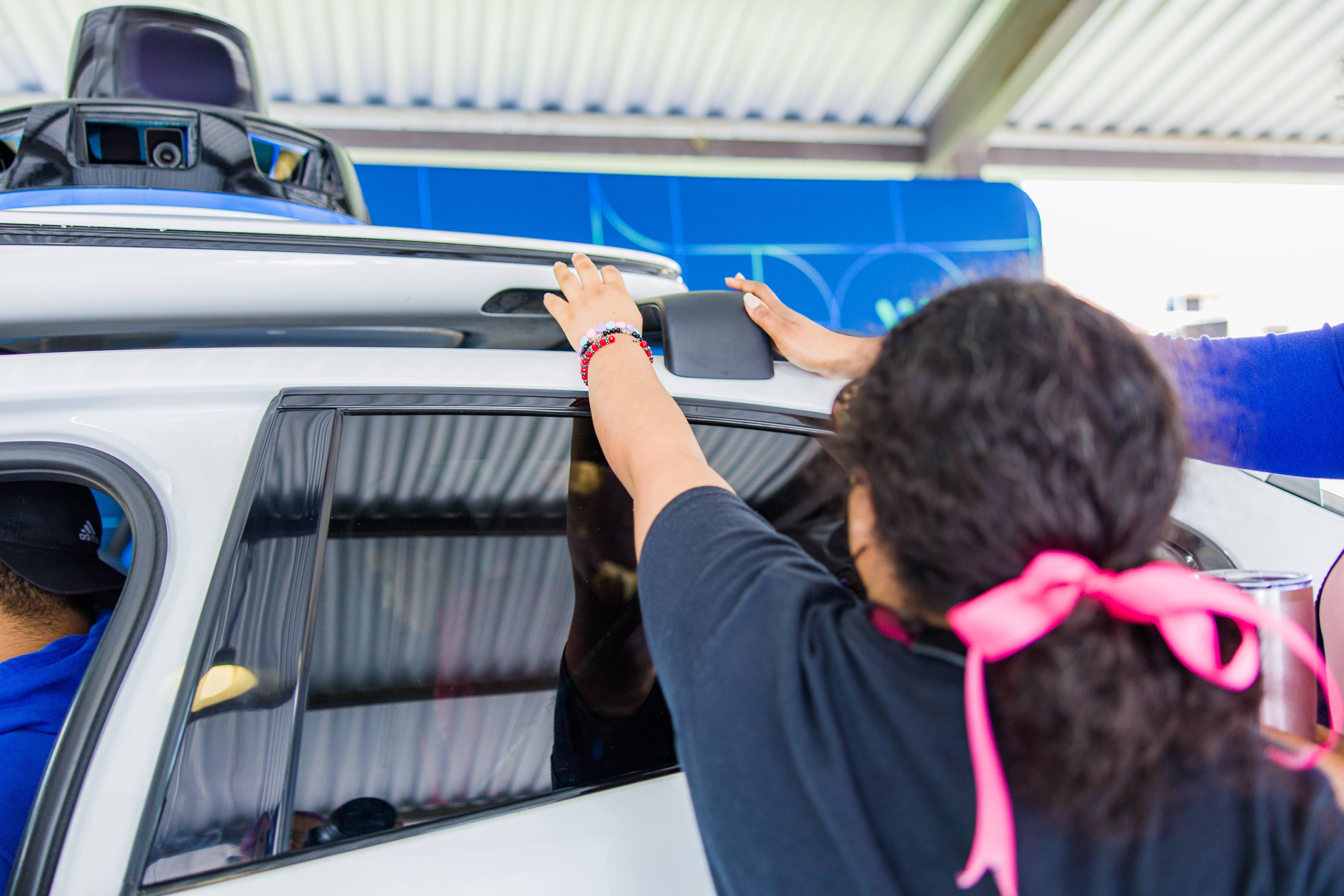 Young girl standing outside of a Waymo vehicle, feeling the edge of the roof