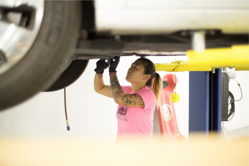 Woman working on a car in auto shop 