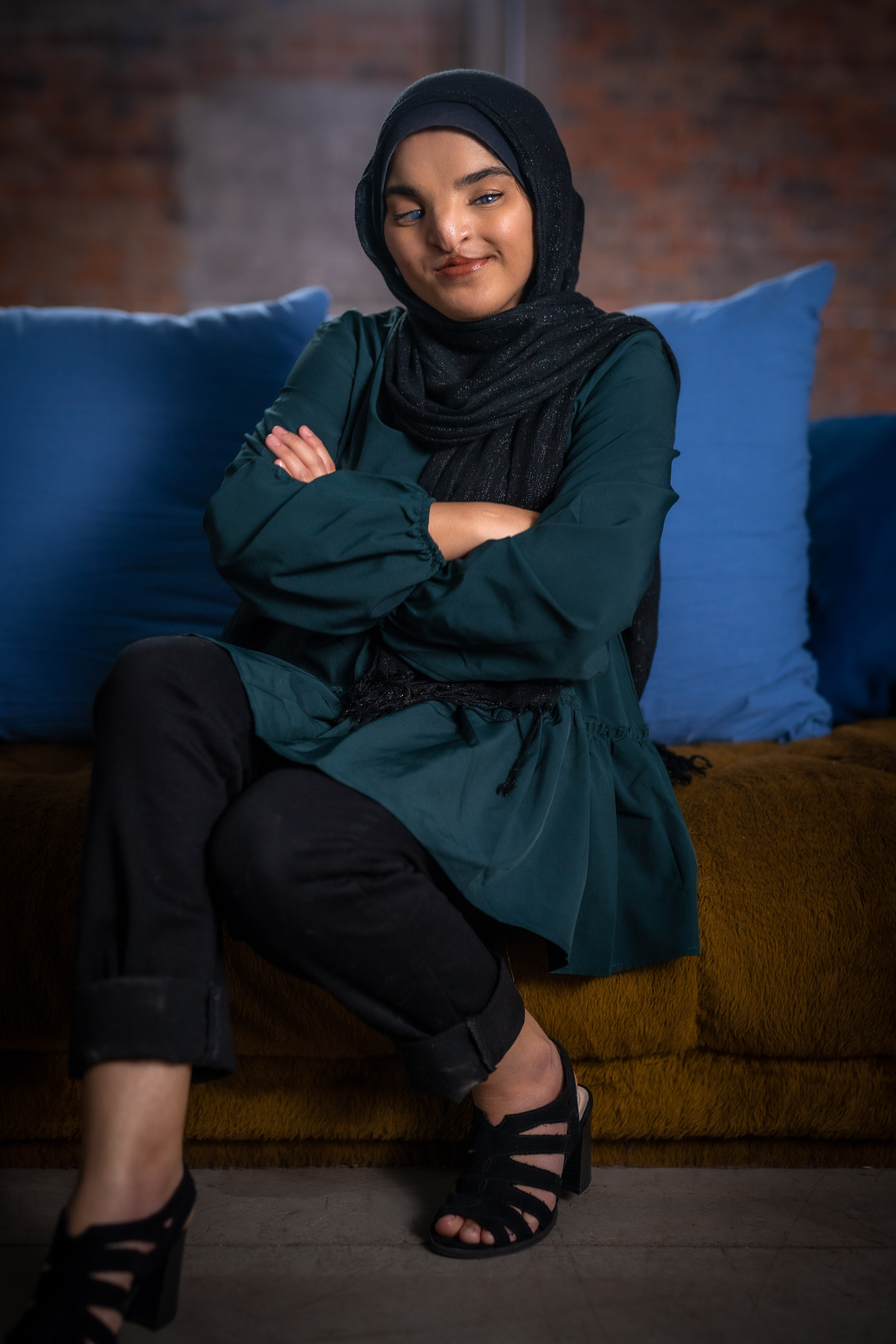 Woman sitting on blue couch with arms crossed