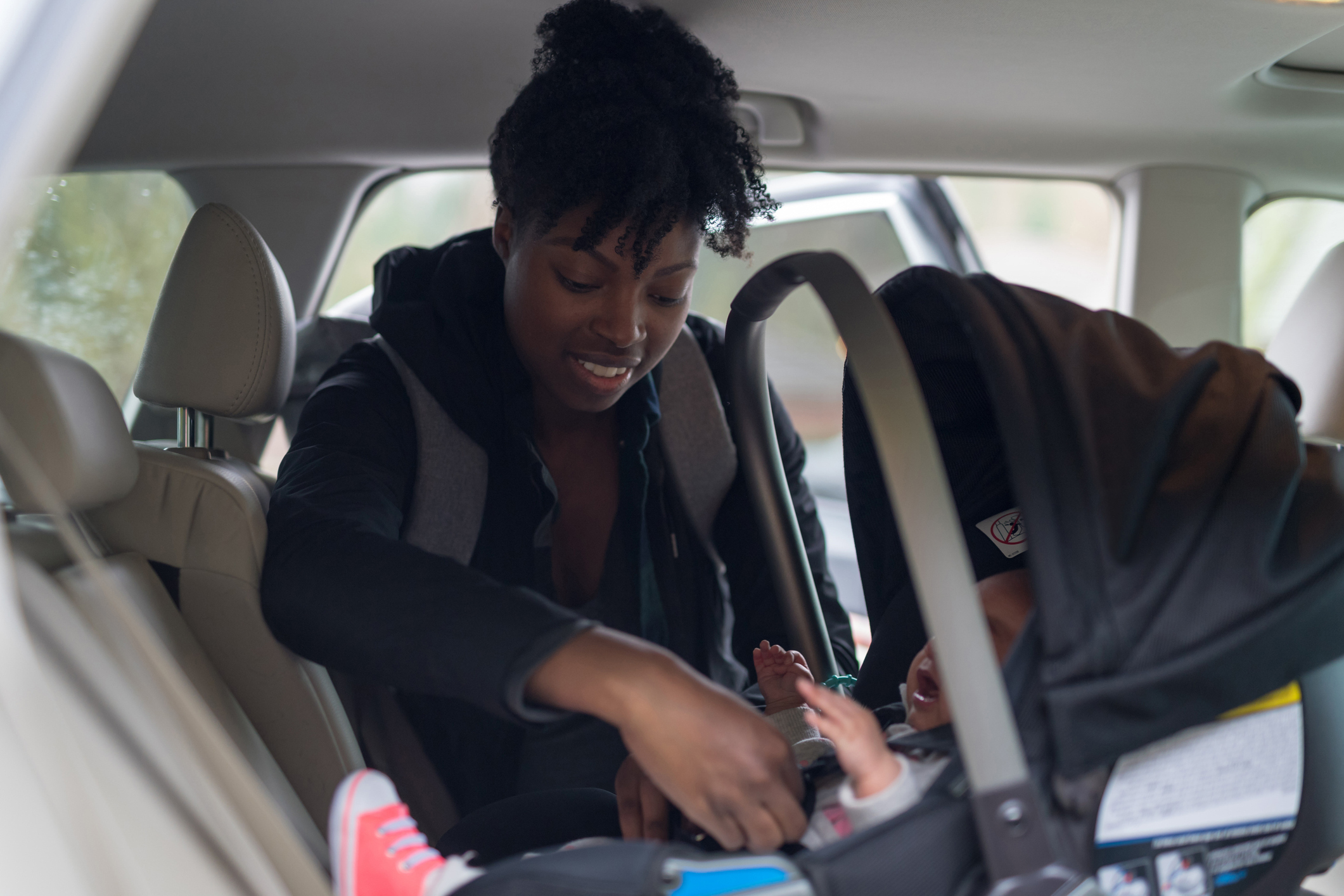Mother buckling infant into carseat 