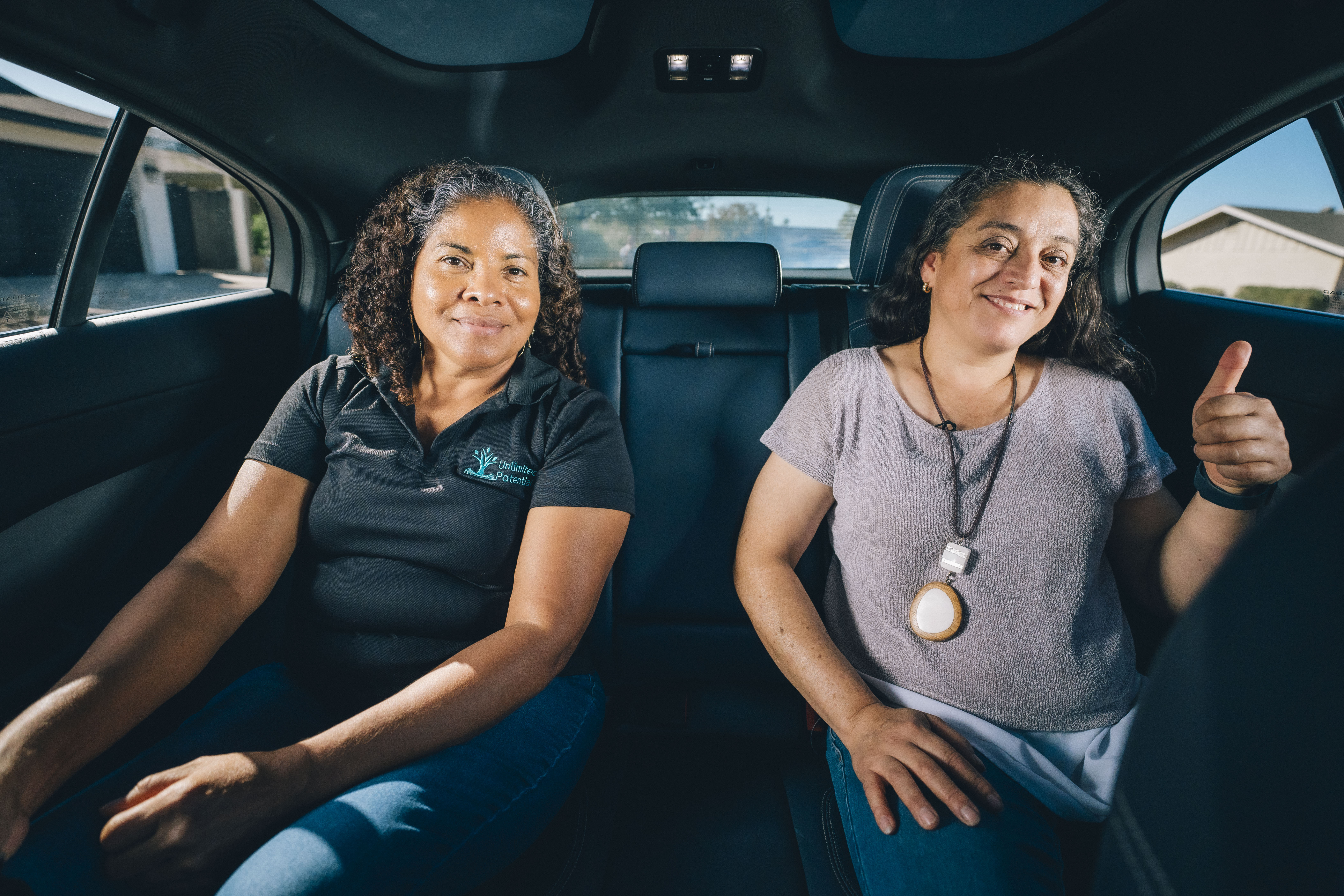 Juana and Minerva sit in the backseat of a fully autonomous Waymo One ride-hailing vehicle