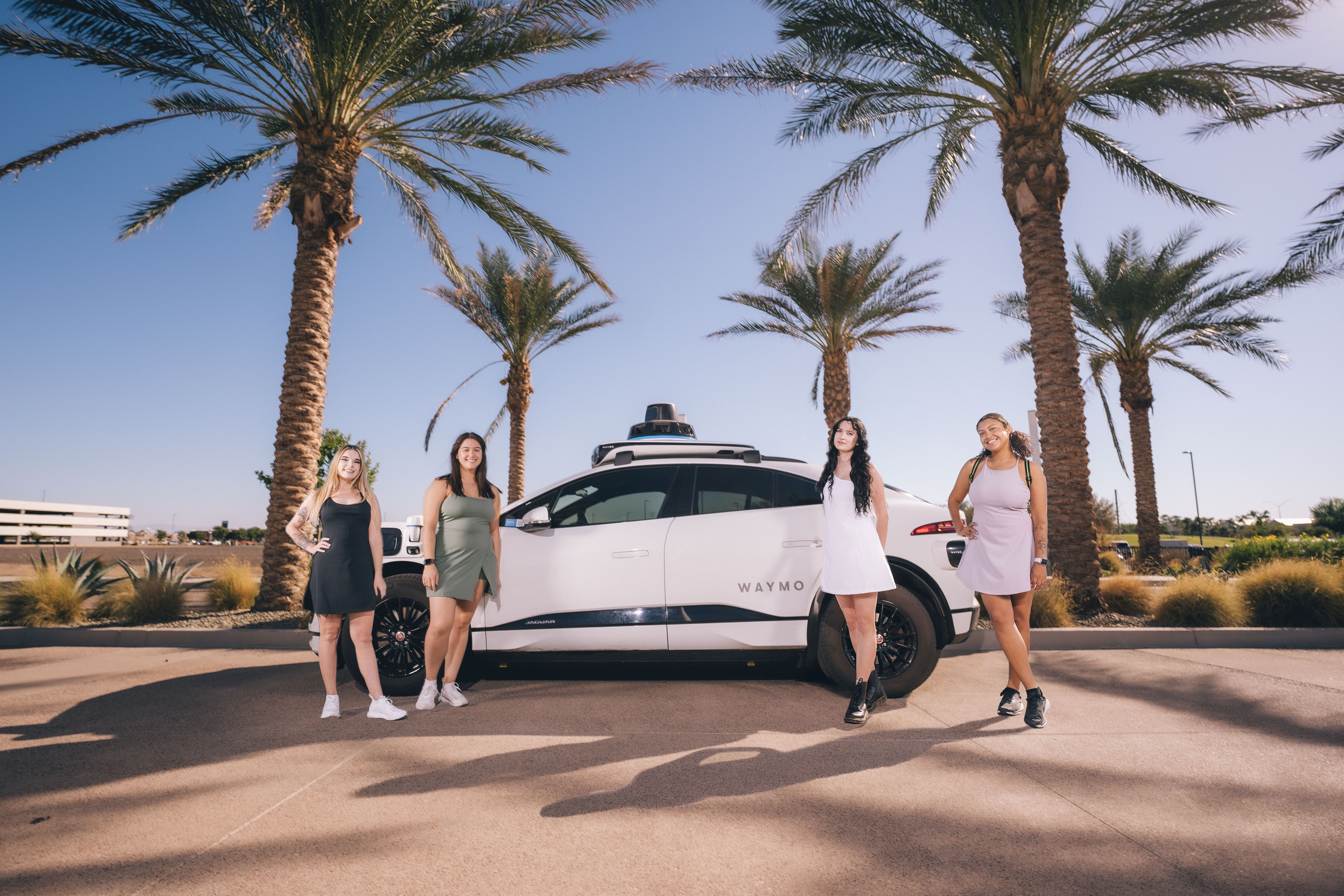 Co-founders Julie, Hope, Grace, and Deysia standing in front of a Waymo autonomous vehicle
