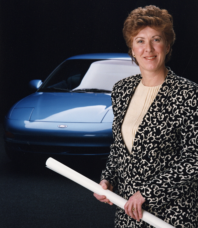 A woman standing in front of blue car