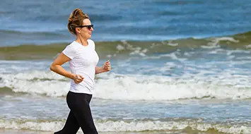 Frau joggt am Strand für Vitamin D