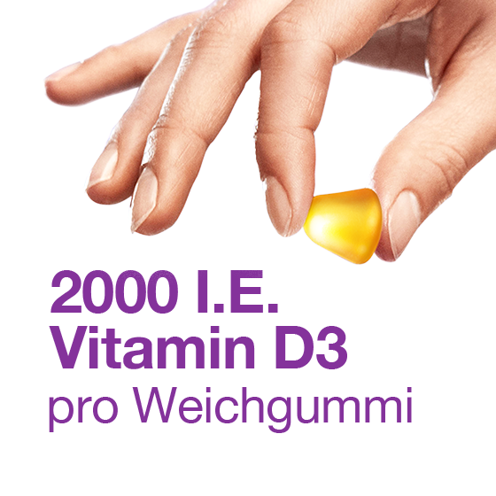Hand hält ein gelbes Weichgummi; Text: 2000 I.E. Vitamin D3 pro Weichgummi.