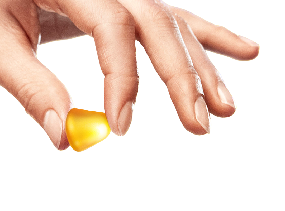 Hand hält ein gelbes VIGANTOLVIT Fruchtgummi zwischen den Fingern vor weißem Hintergrund.