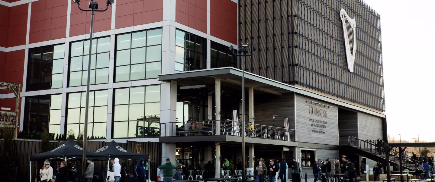 Guinness brewery taproom exterior with visitors on patio and harp logo on building