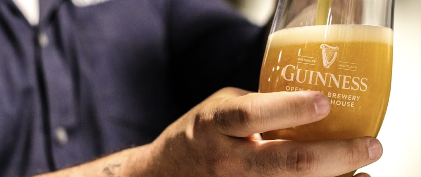 Beer poured into Guinness glass labeled Baltimore Maryland, hand holding glass