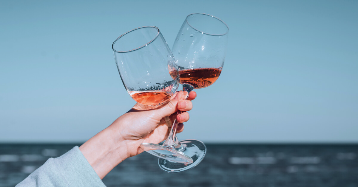 Image of a woman's hand holding 2 glasses of rose