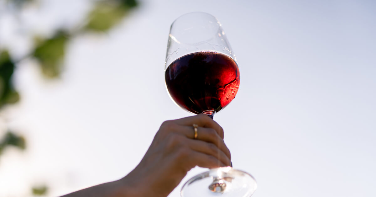 Image of a woman's hand holding a glass of red wine
