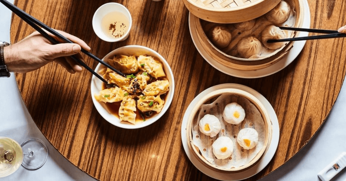 Hands reaching across the table for dumplings.