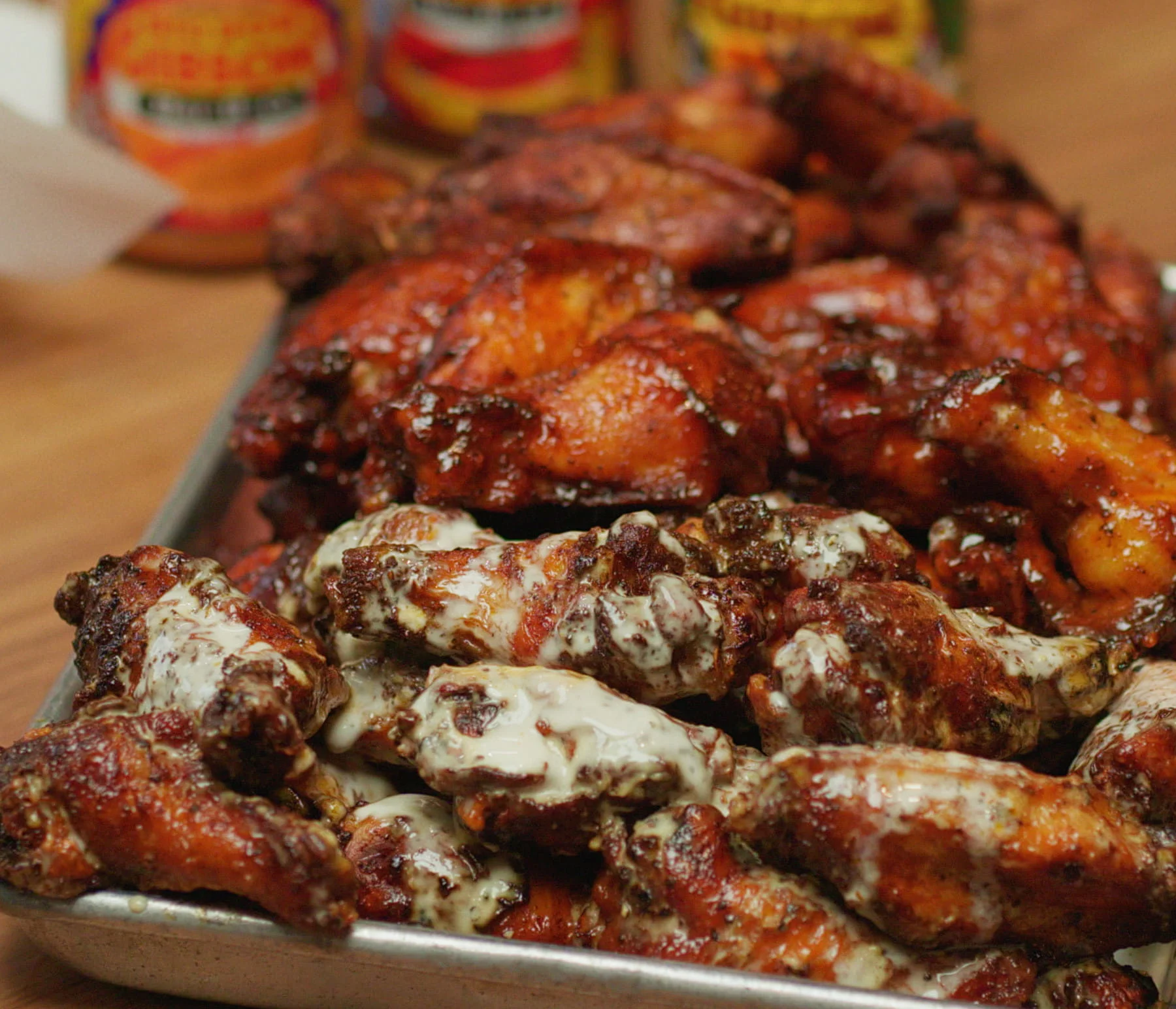 Chicken wings covered in Alabama white sauce on a metal sheet pan