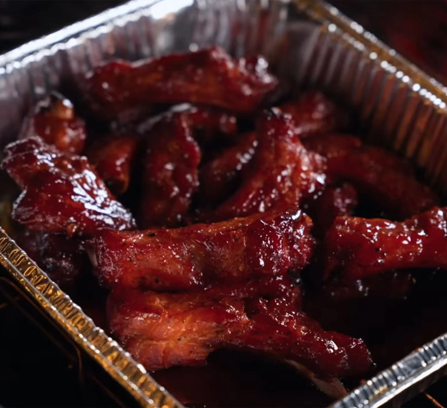 A metal pan filled with grilled saucy pork ribs
