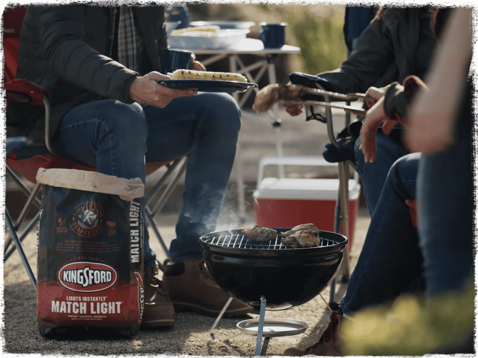 People sitting around a small barbecue grill, a bag of Match Light is in the foreground