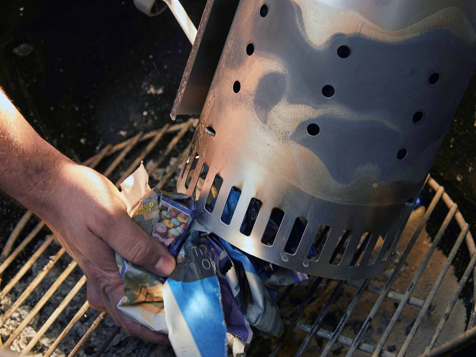 chimney starter charcoal grill setup with briquettes and newspaper
