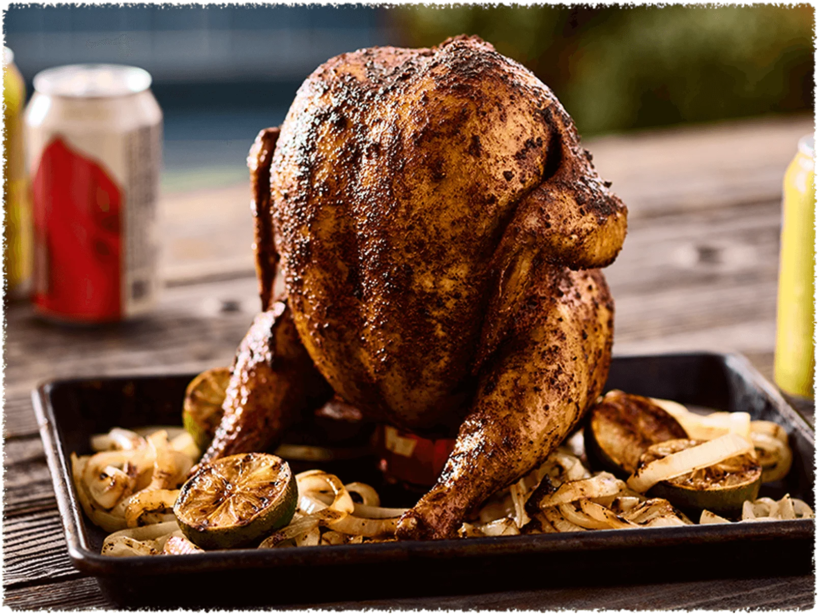 Whole cooked chicken sitting upright on a sheet pan