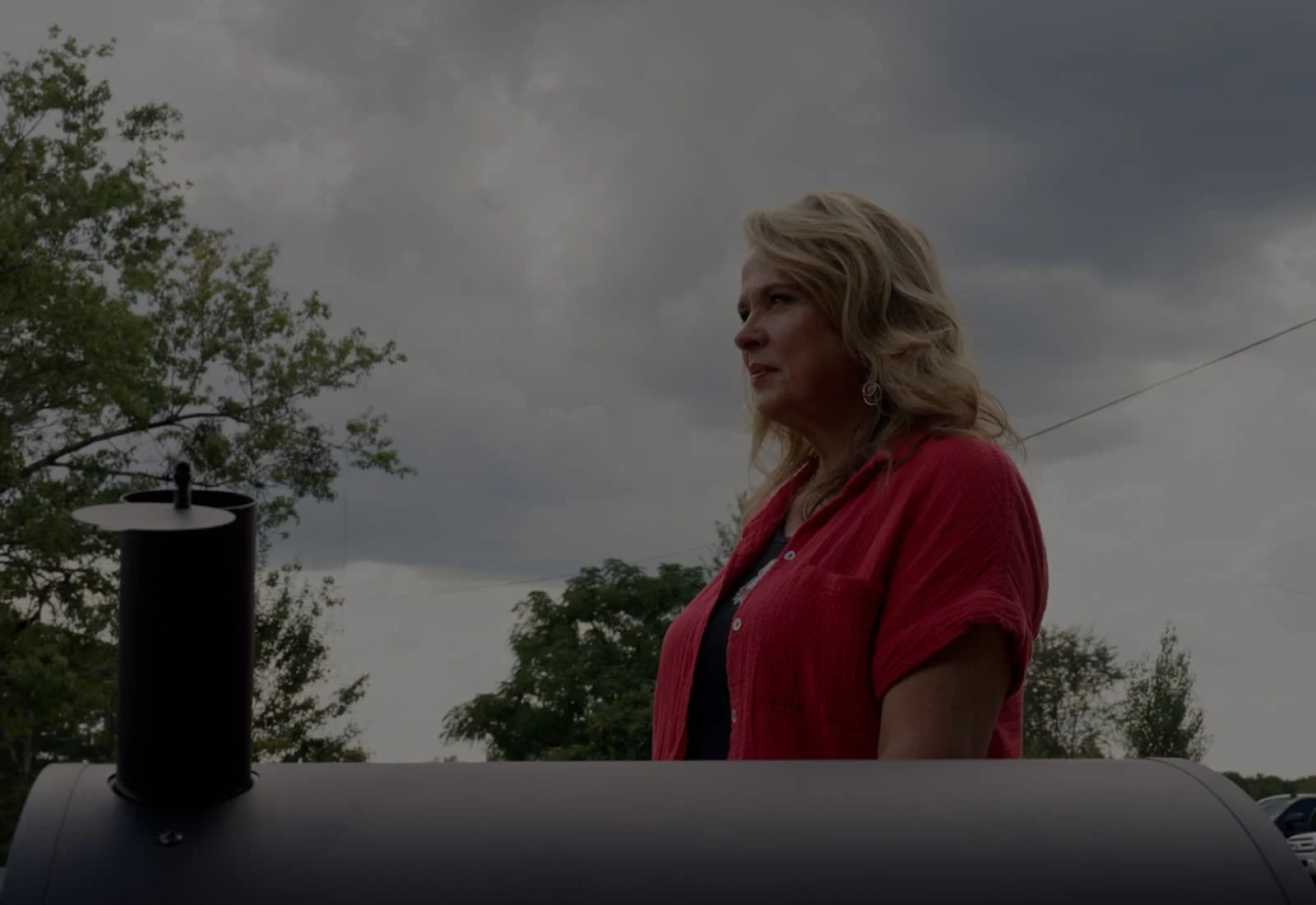 Abbie Hendrix standing next to a grill with a cloudy sky in the background