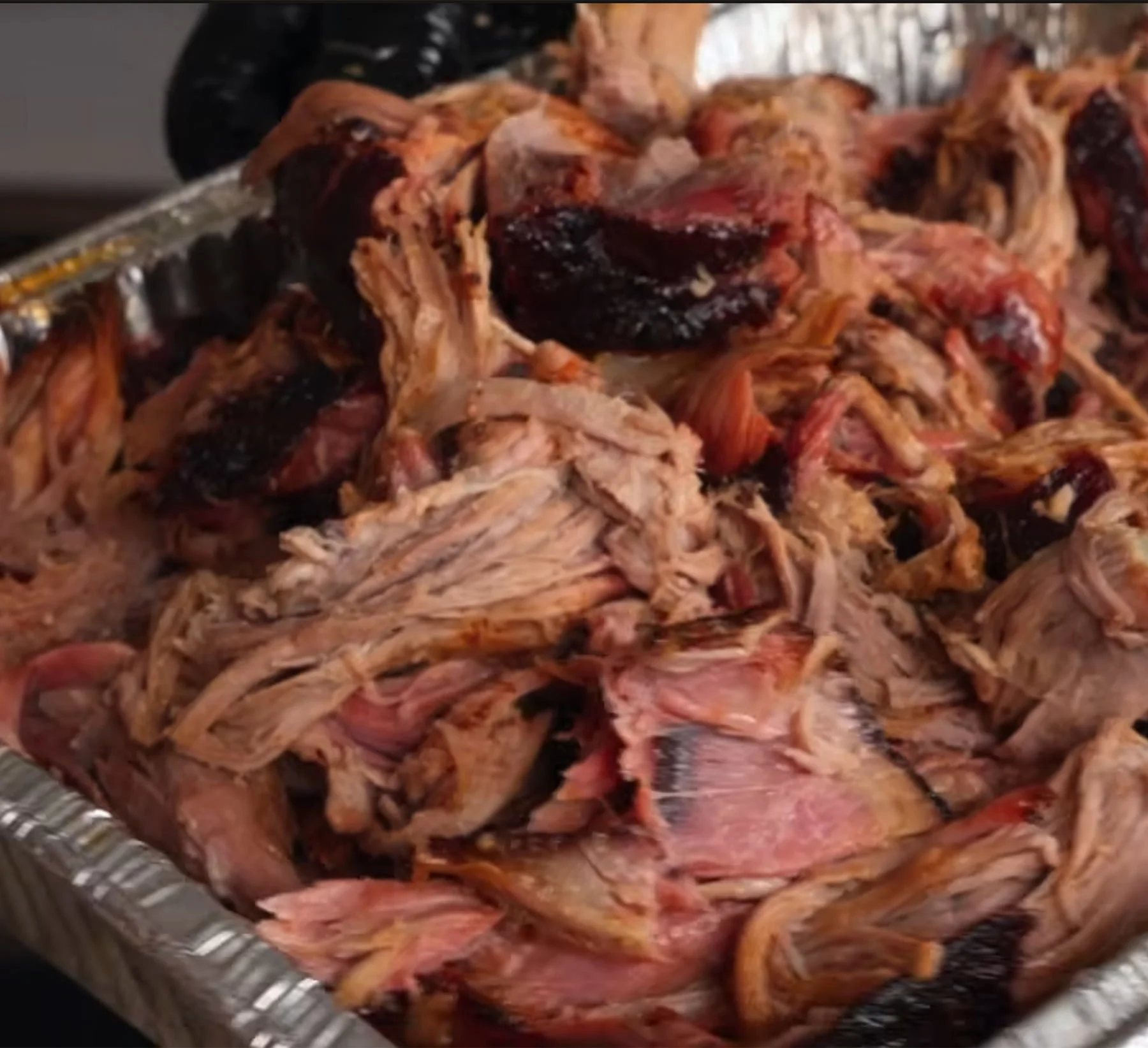 Shredded pulled pork in an aluminum pan