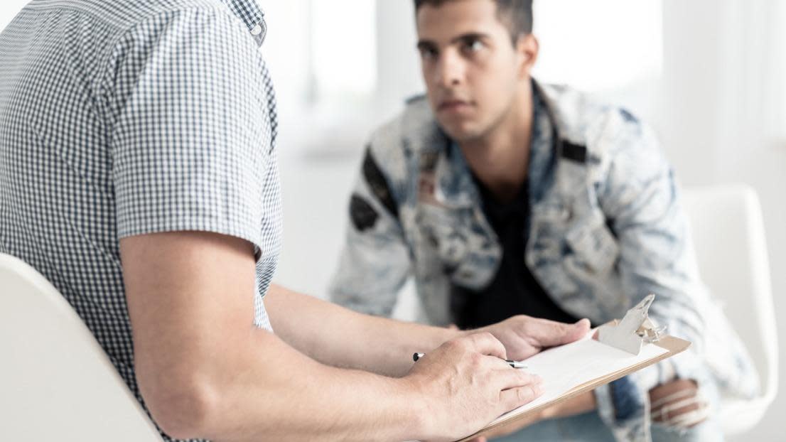 Counselor taking notes while analysing a young man 