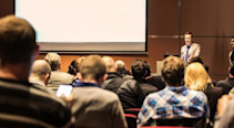 A lecturer giving a talk to students in a lecture hall.