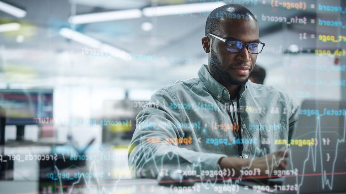 Portrait of motivated Black IT programmer working on laptop computer.