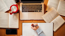 Person at office desk with laptop and books, top view