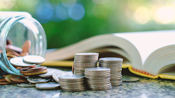 Pile of money, coins in and outside a glass jar
