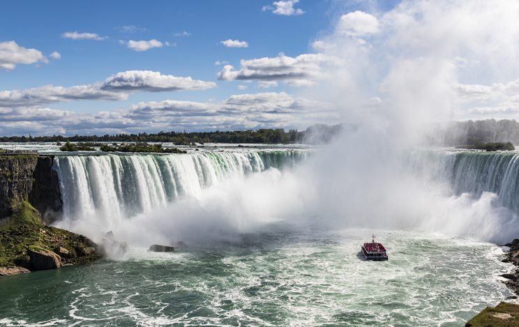 A Maid of the Mist boat tour on the Niagara Falls. The boat is almost enveloped by mist rising from the bottom of the powerful Horseshoe Falls waterfalls.