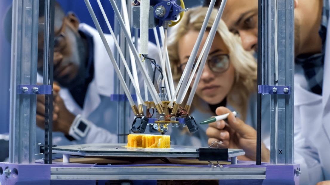 Students watching 3D printing machine in process