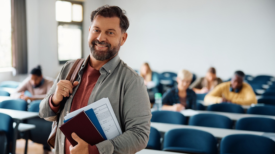 Happy mature student in lecture hall looking at camera