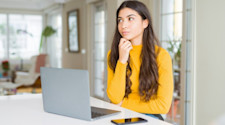 A student thinking while looking at a laptop