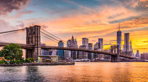 New York City Skyline on the East River with Brooklyn Bridge at sunset.
