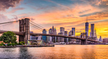 New York City Skyline on the East River with Brooklyn Bridge at sunset.