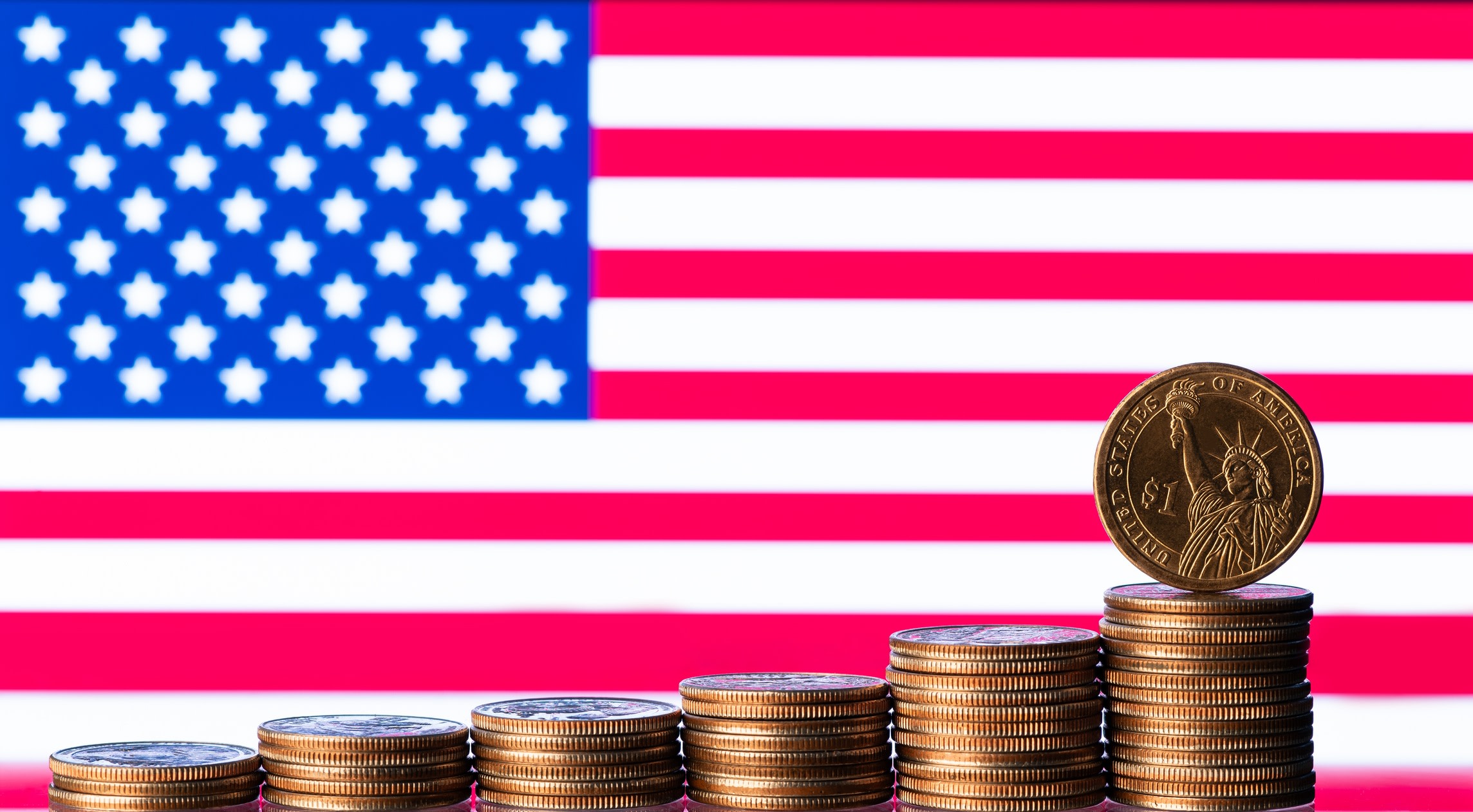 Graphic representing business in the USA, with several piles of American coins forming an ascending bar chart in front of the country's flag