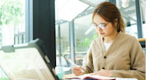 A student using a laptop and writing in a notebook