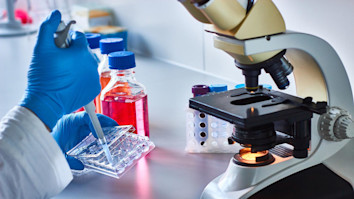 Hands in blue gloves testing in a drug research lab
