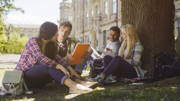 College students having discussion under tree on campus