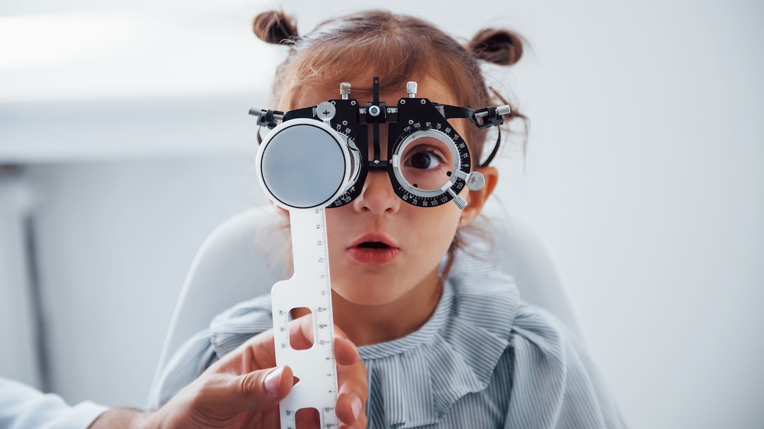 Little girl in eyewear in ophthalmology clinic have test of vision