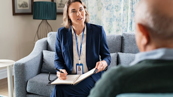 Social worker talking with an old man during home visit