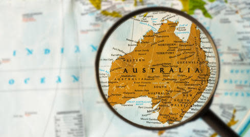 A magnifying glass is held over Australia on a map of the world