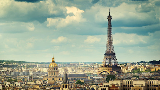 View of Paris with the Eiffel Tower and many other buildings under a cloudy blue sky