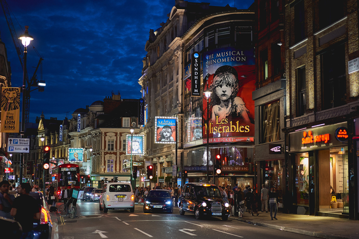 A poster for Les Misérables dominates a busy Shaftesbury Avenue at night in London's West End