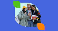 Three students smile while looking at a phone that one of them is holding.