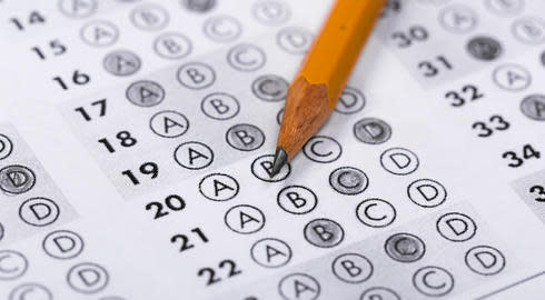 A pencil rests on a paper IELTS test with multiple-choice questions. These have been responded to by one of the letters A, B, C and D being highlighted next to each question.