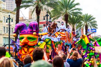 : Mardi Gras parades through the streets of New Orleans. People are celebrating and welcoming locals and visitors. This is the biggest annual celebration of the city.