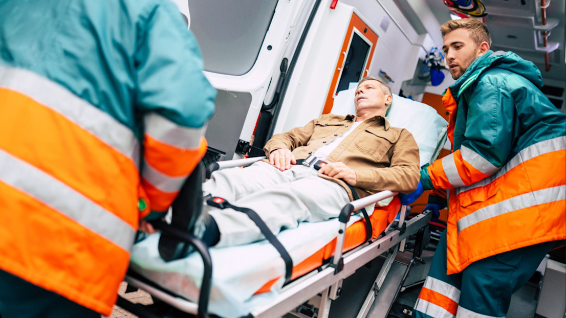 Two paramedics wheeling an injured man into an ambulance